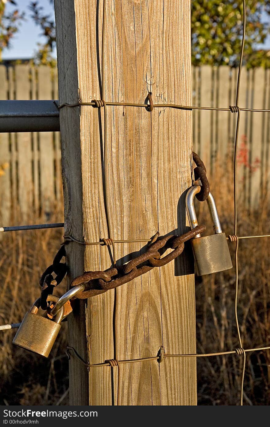 Old locks and a rusty chain on a post and fence. Old locks and a rusty chain on a post and fence