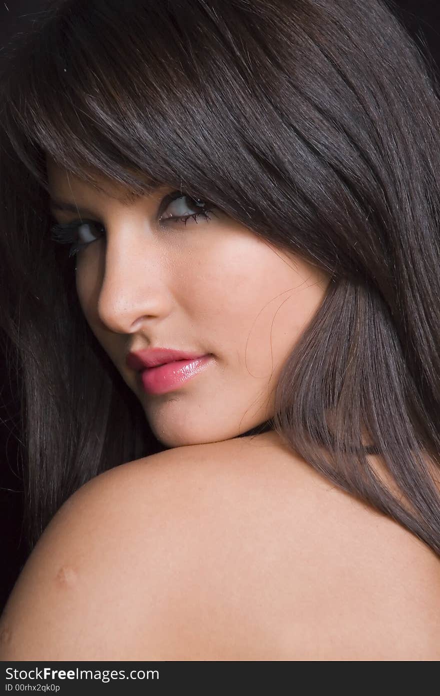 Young brunette girl in red dress on black background.