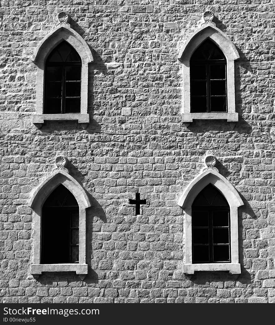 Brick wall with gothic windows and cross. B&W image.