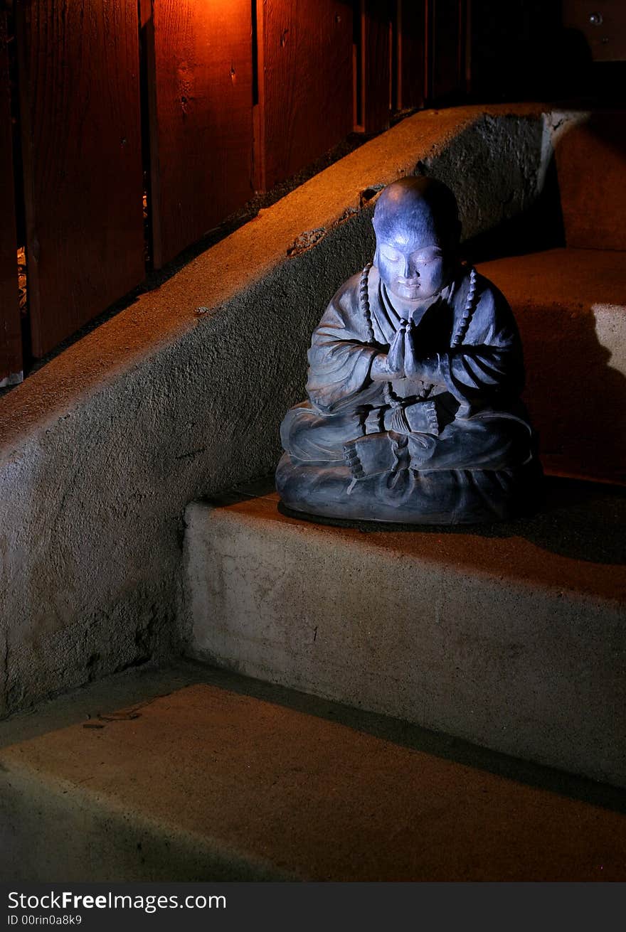 A praying Buddha statue glows in the moonlight. A praying Buddha statue glows in the moonlight