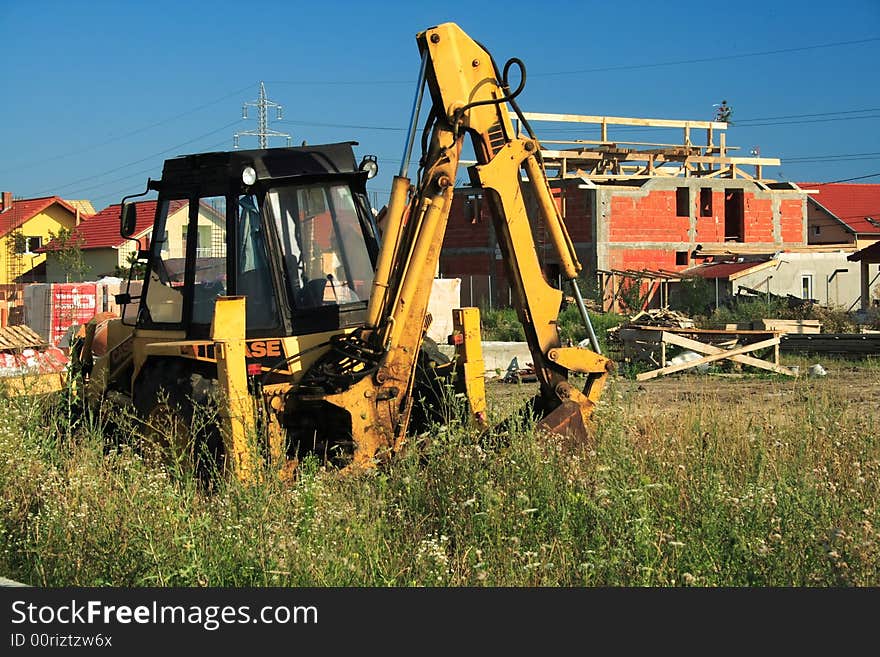 Bright yellow bulldozer on a sunny day in new residential area