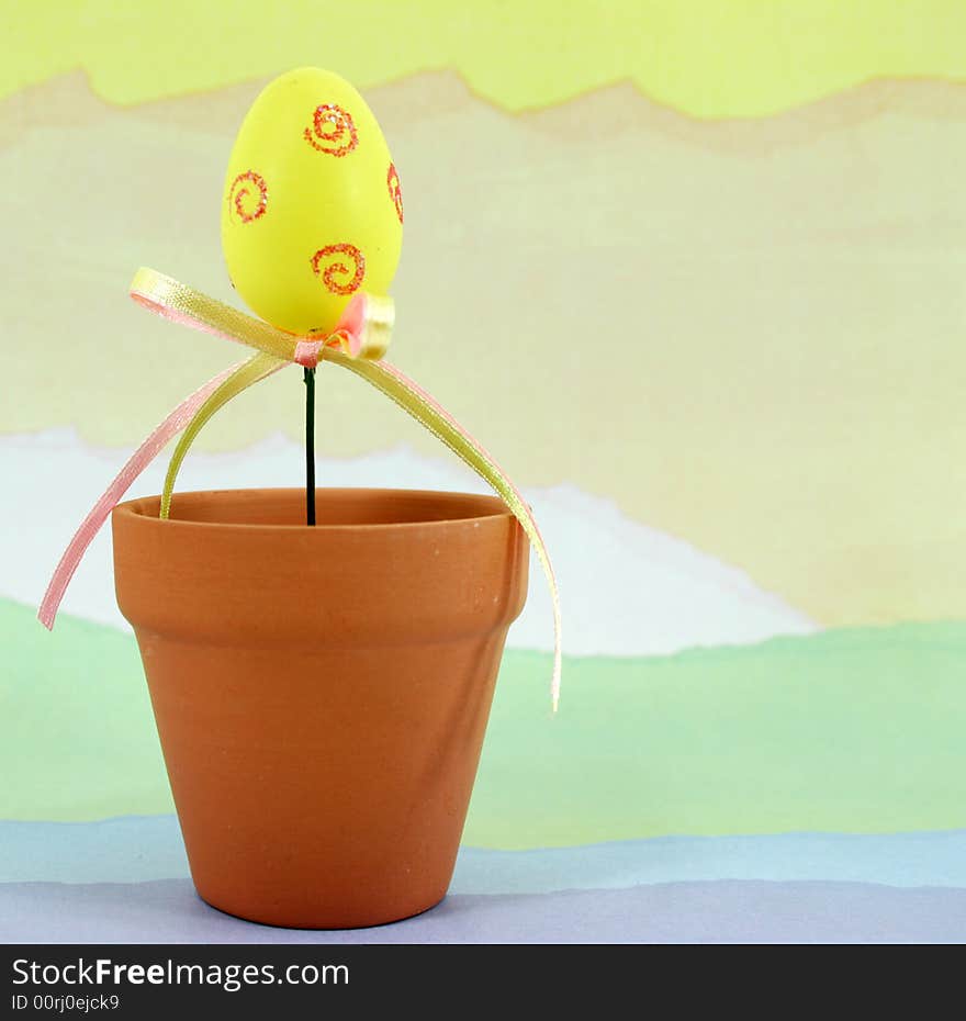 Yellow decorated Easter egg in a terracotta flowerpot on a pastel colored background. Yellow decorated Easter egg in a terracotta flowerpot on a pastel colored background.