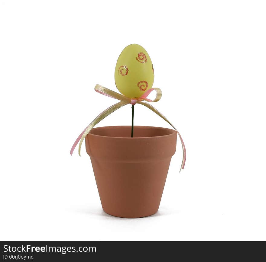 A decorated yellow Easter egg grows out of a terracotta flowerpot. A decorated yellow Easter egg grows out of a terracotta flowerpot.