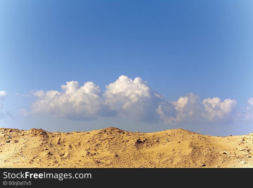 Sandy dune. The blue sky. Clouds