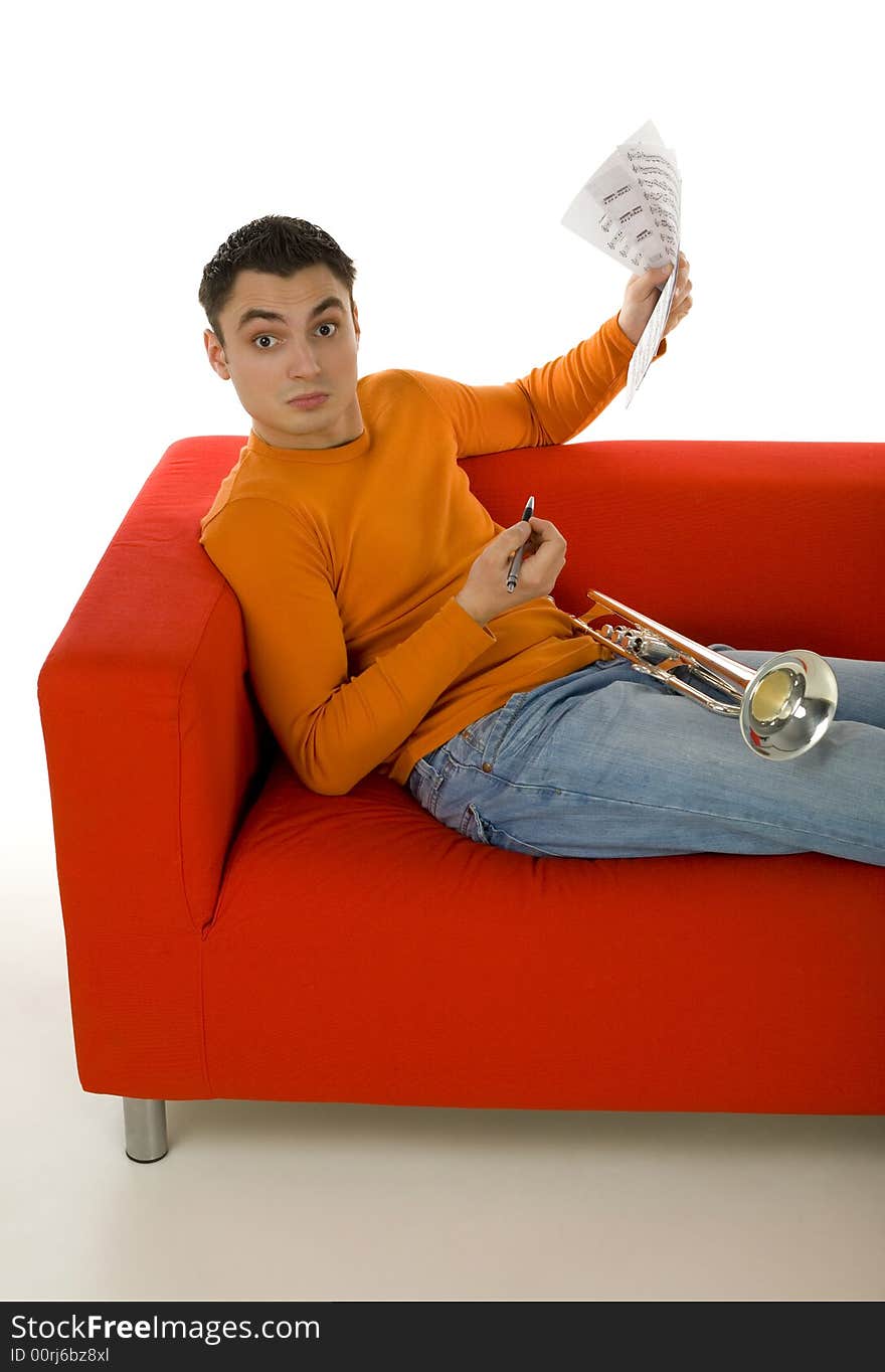 Trumpeter sitting on red couch and composing music, holding sheet music in hands.  Looking at camera. White background. Trumpeter sitting on red couch and composing music, holding sheet music in hands.  Looking at camera. White background.