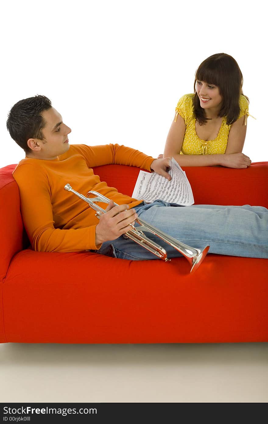 The man sitting on couch and holding trumpet and sheet music in hands. The woman standing behind couch. They're looking at each other. White background. The man sitting on couch and holding trumpet and sheet music in hands. The woman standing behind couch. They're looking at each other. White background.