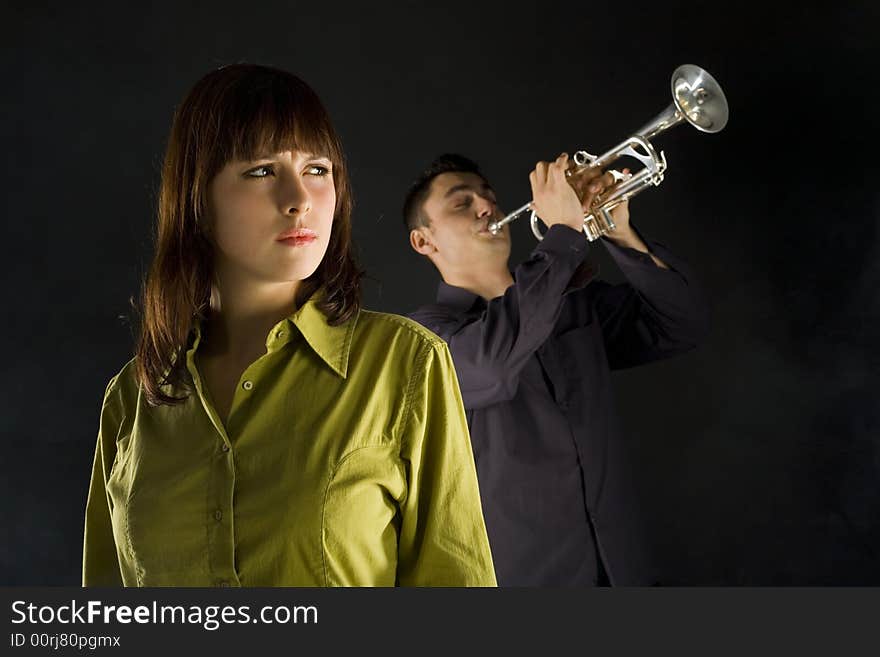 Trumpet man standing behind the woman. The woman looks thoughtful. Front view. Trumpet man standing behind the woman. The woman looks thoughtful. Front view.