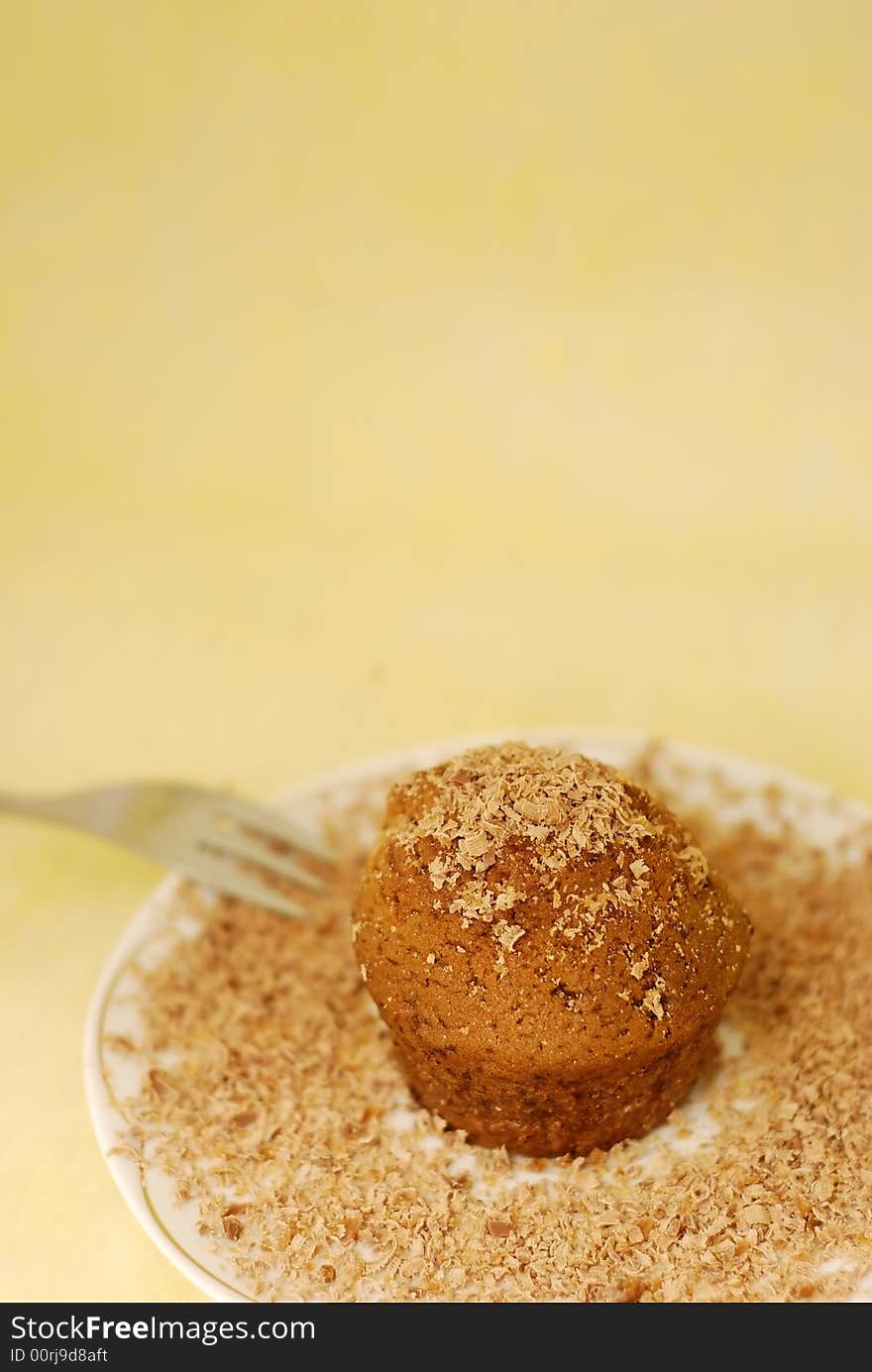 Chocolate muffin with small chocolate pieces on the plate with fork