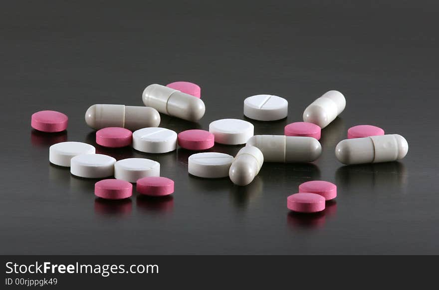 Red and white tablets and pills isolated on a black background. Red and white tablets and pills isolated on a black background