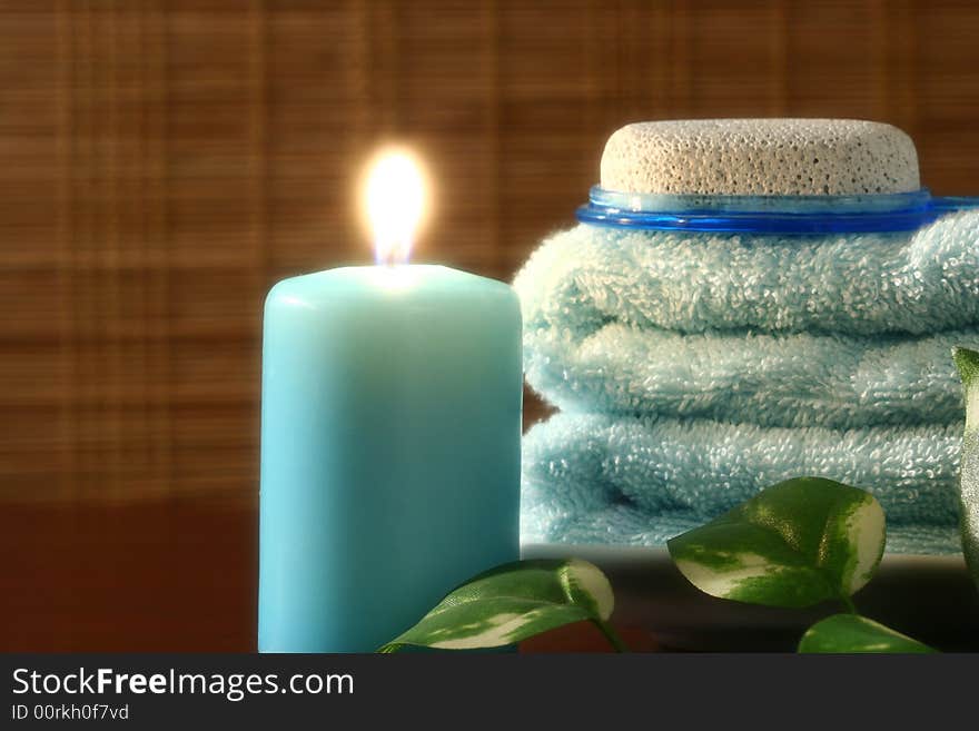 Blue candle and towel, green leaf and pumice in front of bamboo blind. Blue candle and towel, green leaf and pumice in front of bamboo blind