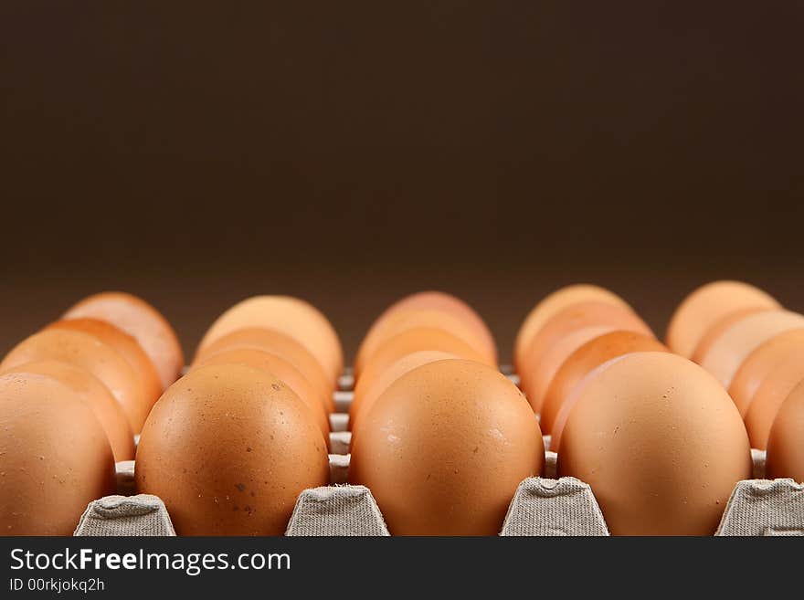 24 eggs in tray over brown background