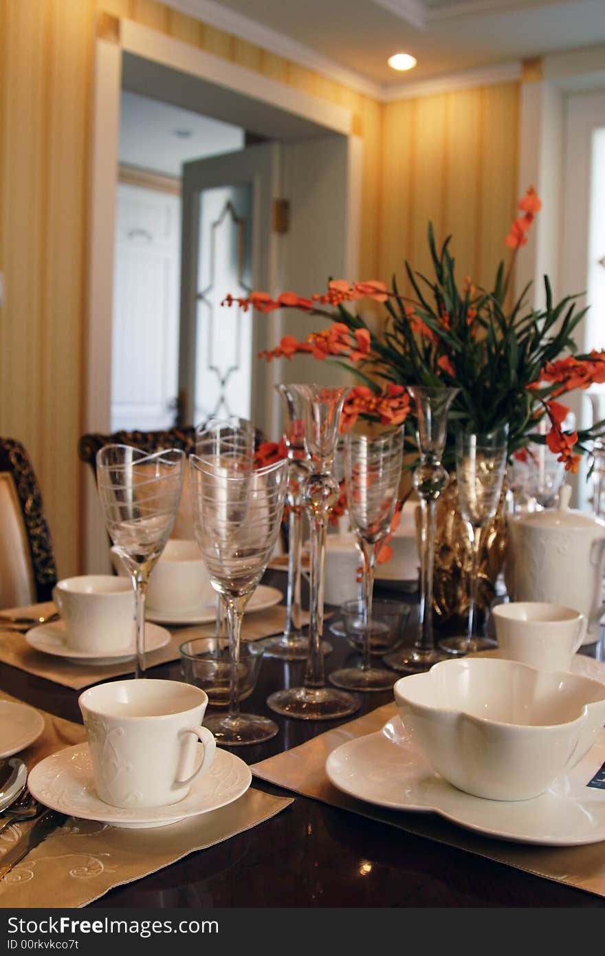 A table with many plates bowls and glasses in luxury dining room.