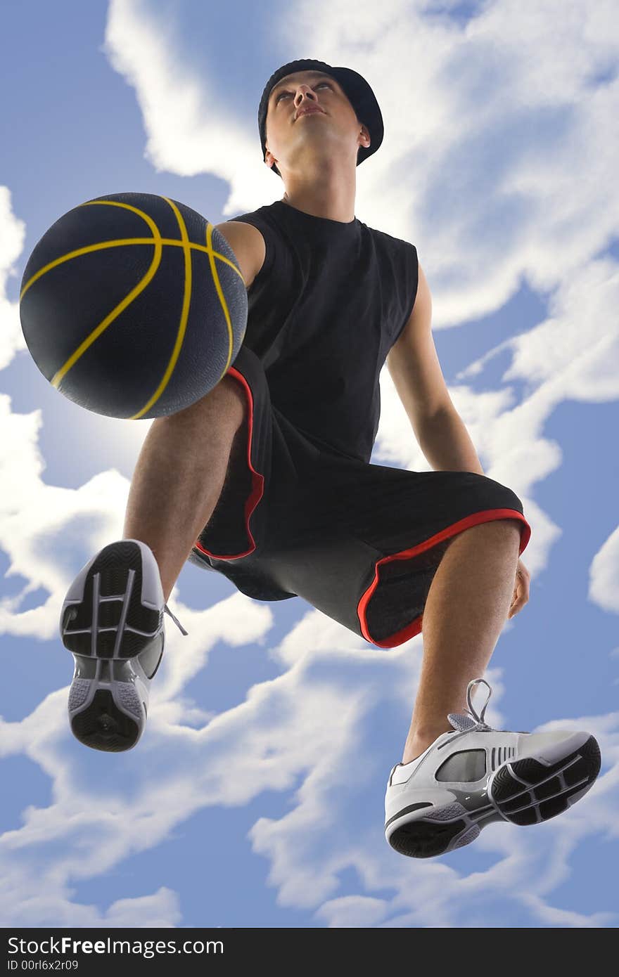 Young basketball player dribbling ball. Looking at something. Low angle view. Young basketball player dribbling ball. Looking at something. Low angle view