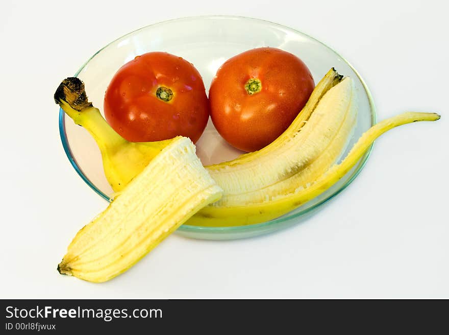 Peeled banana with  tomatoes on glass plate on white background. Peeled banana with  tomatoes on glass plate on white background