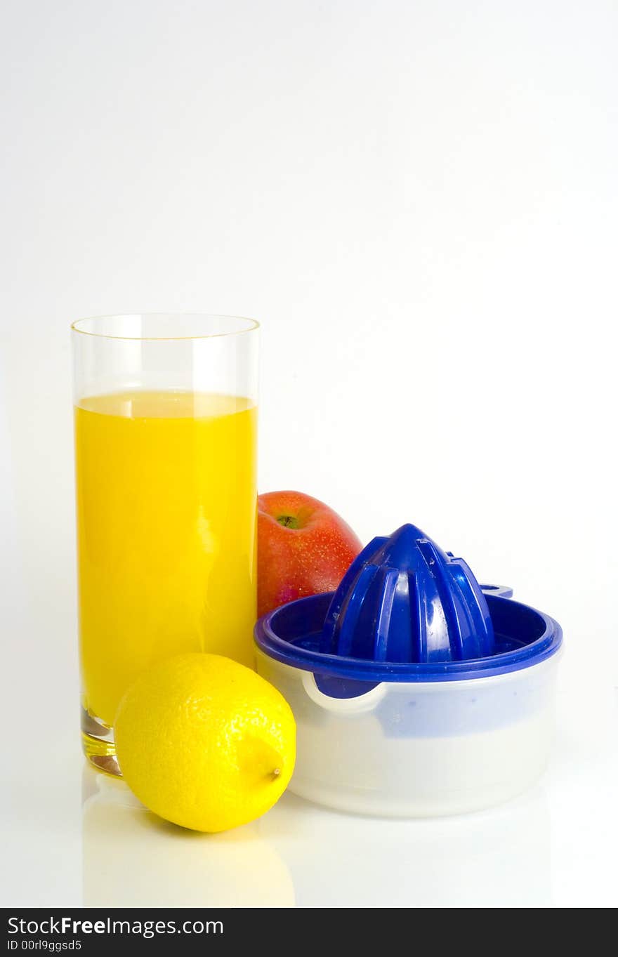 Big transparent glass of orange juice, yellow lemon, red apple and squeezer on white background. Big transparent glass of orange juice, yellow lemon, red apple and squeezer on white background