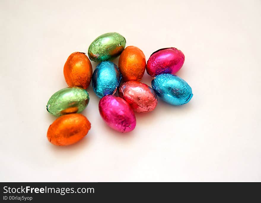 Colourful selection of minature foil wrapped chocolate easter eggs on white background