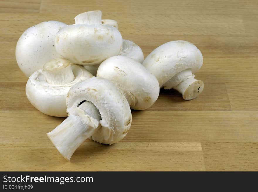 Button mushroom (Agaricus bisporus) on wooden chopping board. Button mushroom (Agaricus bisporus) on wooden chopping board