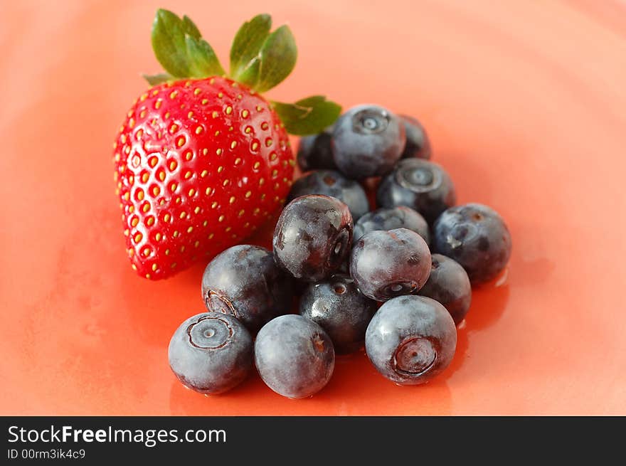 Blueberries and raspberry on ceramic plate