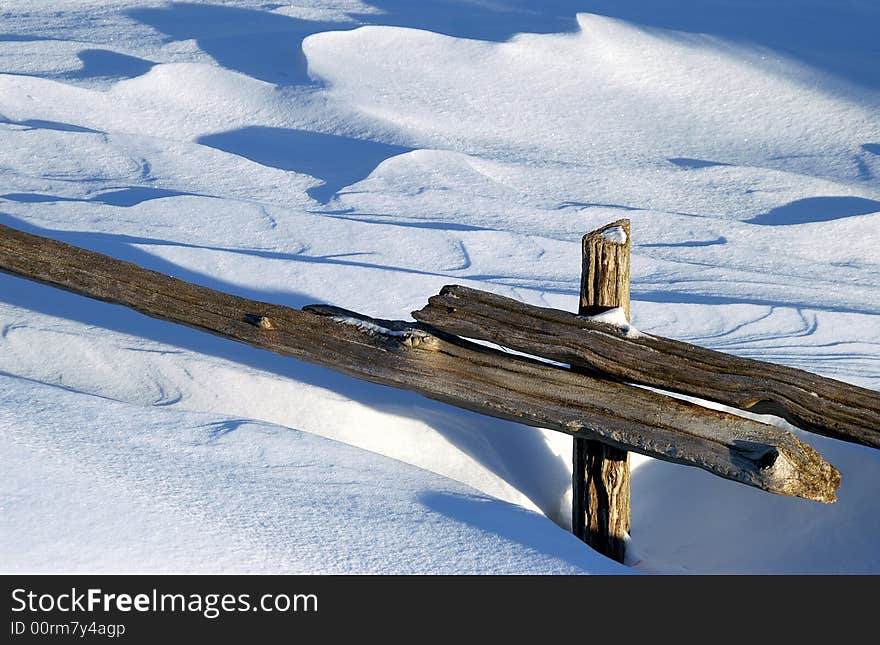 Snow drift buries split rail fence in wind-swept field. Snow drift buries split rail fence in wind-swept field