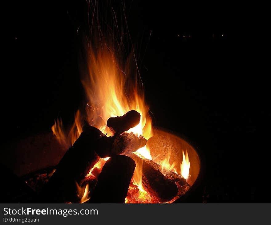 Campfire burning inside a fire-ring as found at many campgrounds. Campfire burning inside a fire-ring as found at many campgrounds