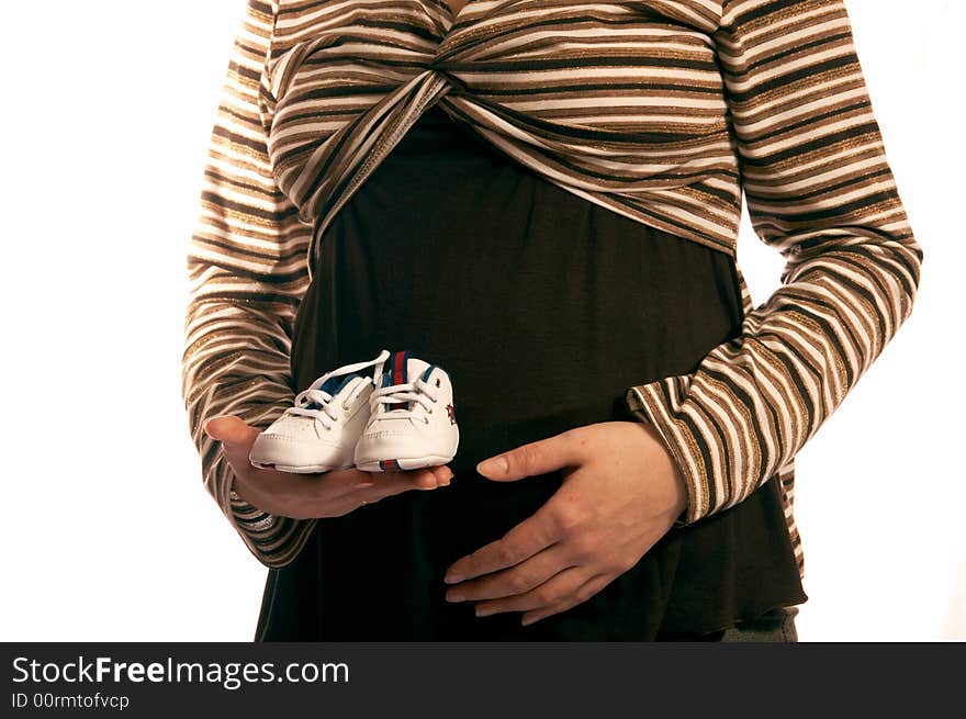 The pregnant woman on a white background. In hands holds small boots