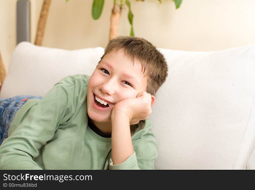 Happy teenager lie on sofa at home. Smile have no one cuspid tooth.