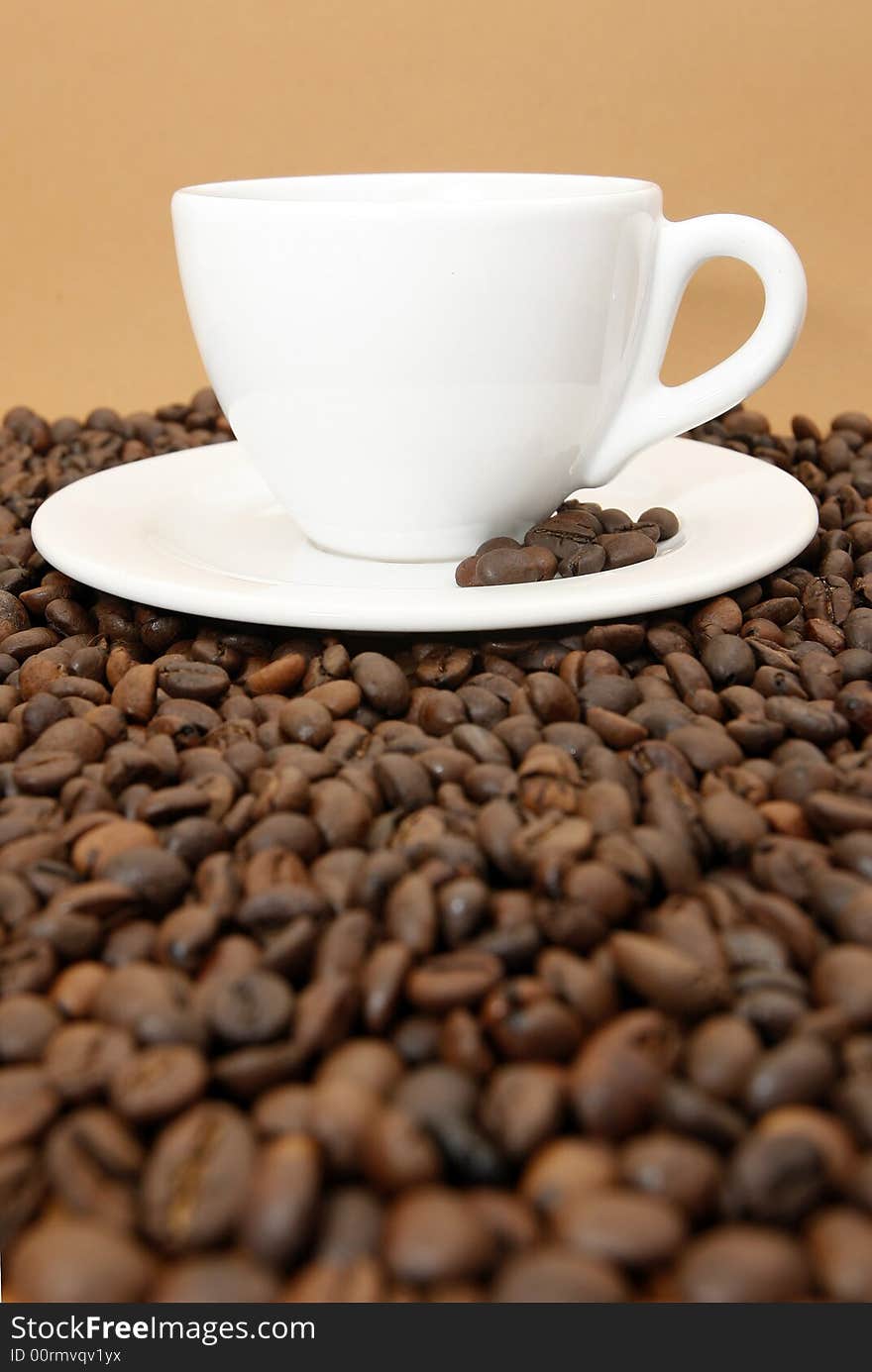 White coffee cup with coffee beans on brown background