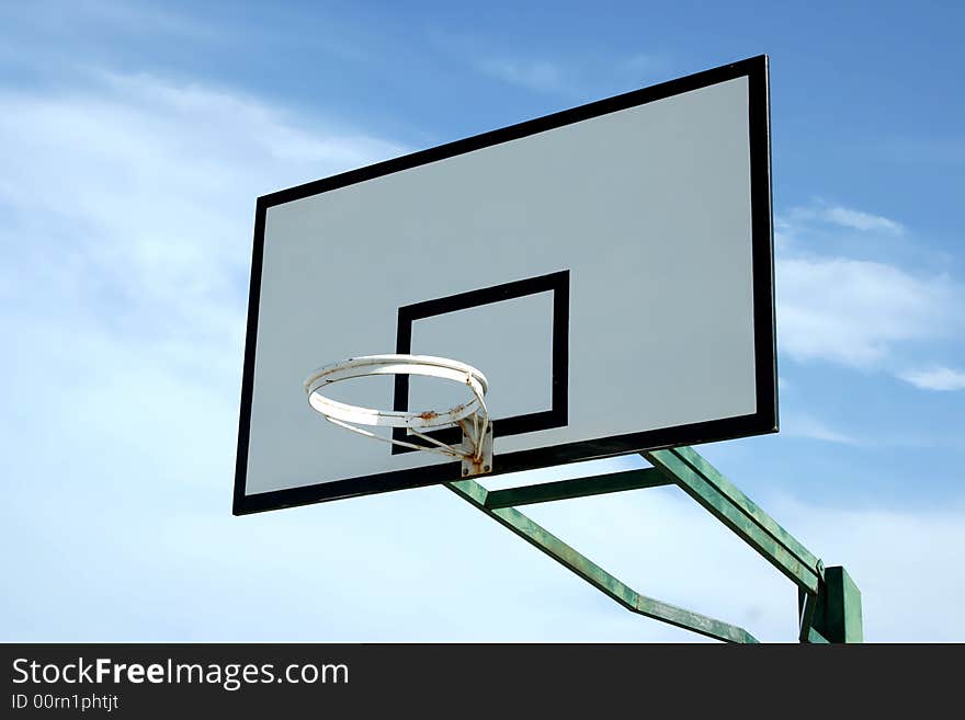 Old basketball basket in blue sky with some clouds