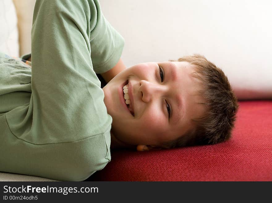 Happy teenager lie on red sofa at home