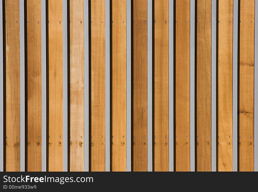 The horizontal striping of a wood and metal gate.