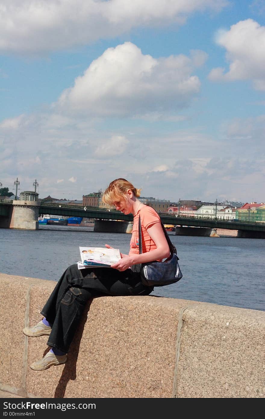 Girl reading magazine on canal border in Saint Petersburg