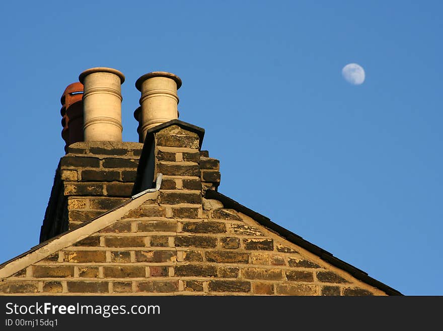 This is a shot of an old building in London with the moon out in the daytime. This is a shot of an old building in London with the moon out in the daytime