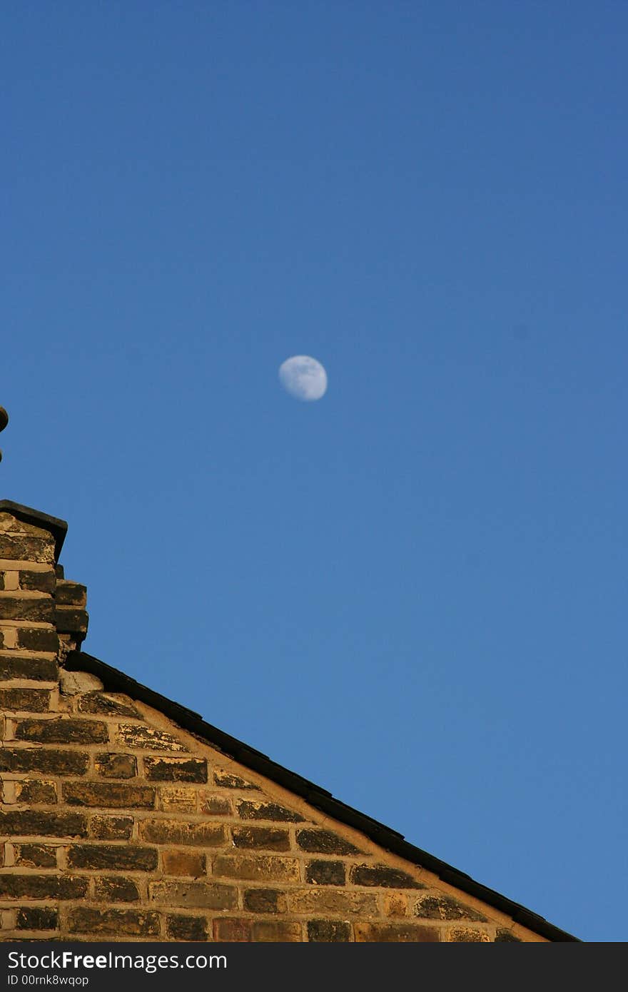 This is a shot of an old building in London with the moon out in the daytime. This is a shot of an old building in London with the moon out in the daytime