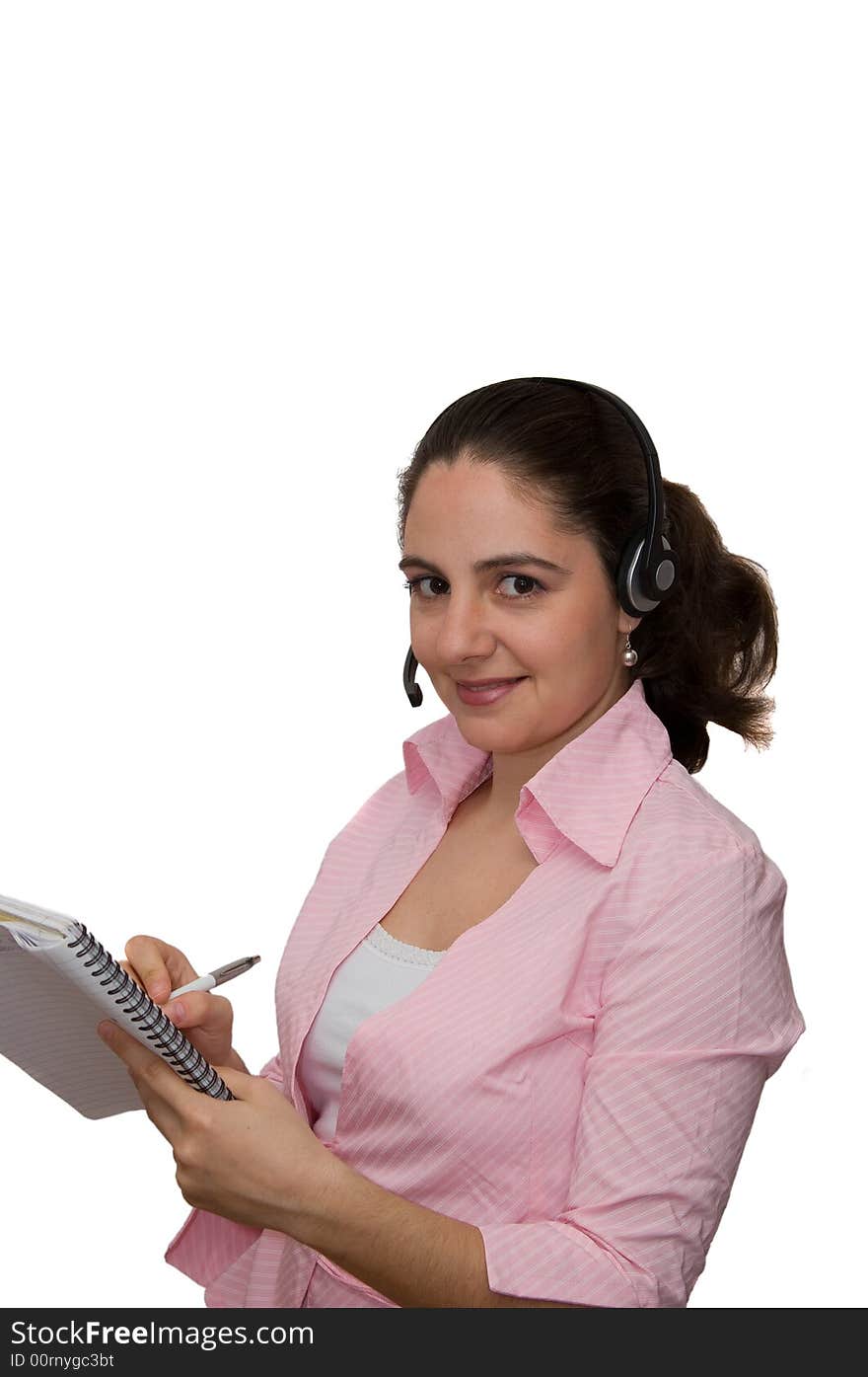 A girl, wearing headphones and microphone, taking notes, smiling. A girl, wearing headphones and microphone, taking notes, smiling