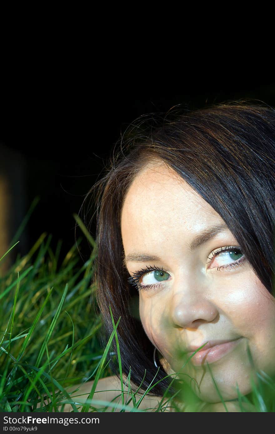 Young beautiful dark-haired woman lying at grass and smiling. Young beautiful dark-haired woman lying at grass and smiling