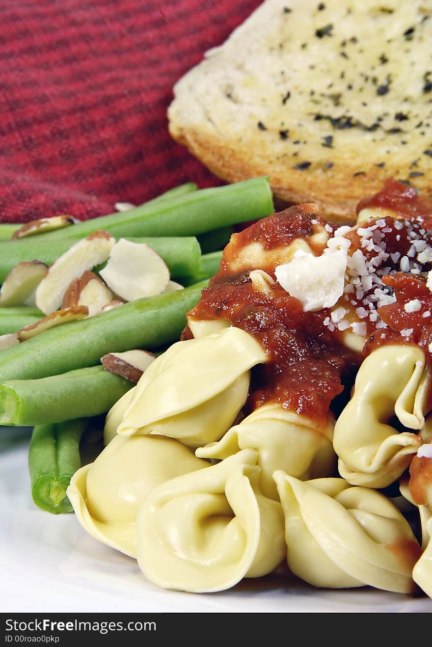 Tortellini with sauce and green beans and bread. Tortellini with sauce and green beans and bread.