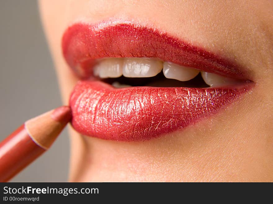 Applying cosmetics on the beautiful woman's lips. Applying cosmetics on the beautiful woman's lips