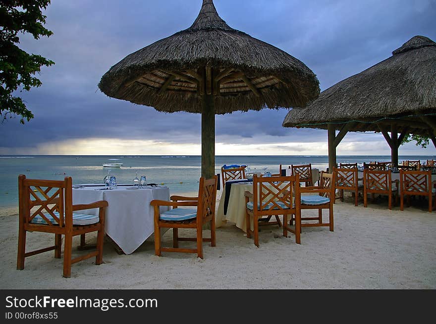 Tropical restaurant tables on beach at sunset