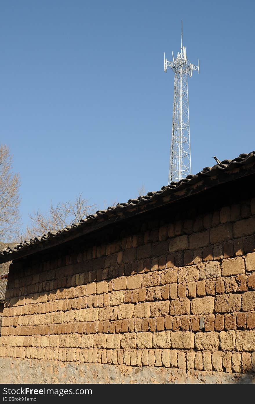 A silver shining cell tower stands behind an old wall which was built with mud bricks. Taken in Lijiang, which is an 800-year-old town in Yunnan Province, China. A silver shining cell tower stands behind an old wall which was built with mud bricks. Taken in Lijiang, which is an 800-year-old town in Yunnan Province, China.