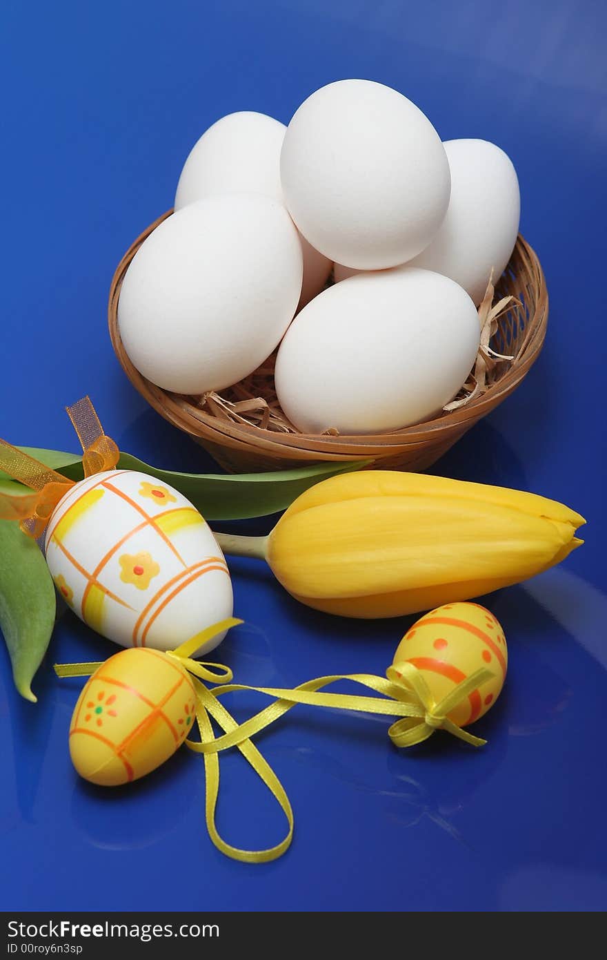 Easter eggs with yellow tulip on blue background.