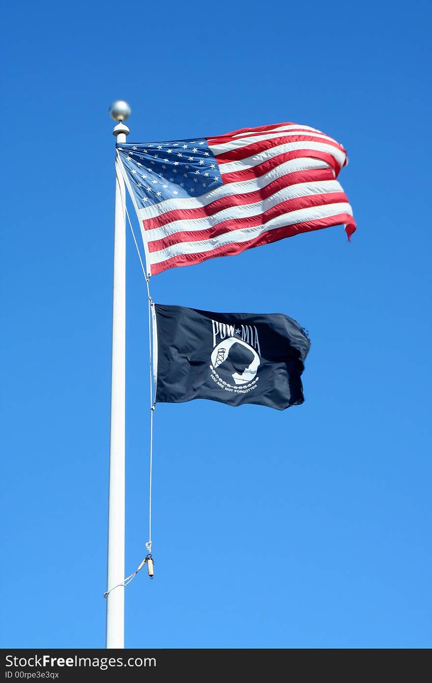 A American and POW flags against a blue sky