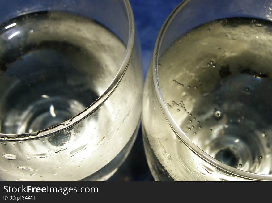 Close-up of two champagne glasses filled with bubbly on a blue background. Close-up of two champagne glasses filled with bubbly on a blue background