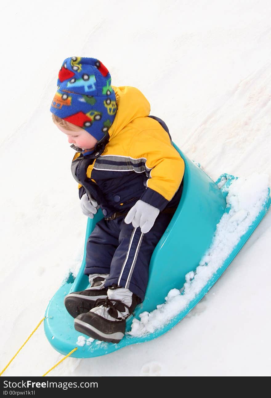 Young Boy Sledding in fresh snow in colorful outfit. Young Boy Sledding in fresh snow in colorful outfit