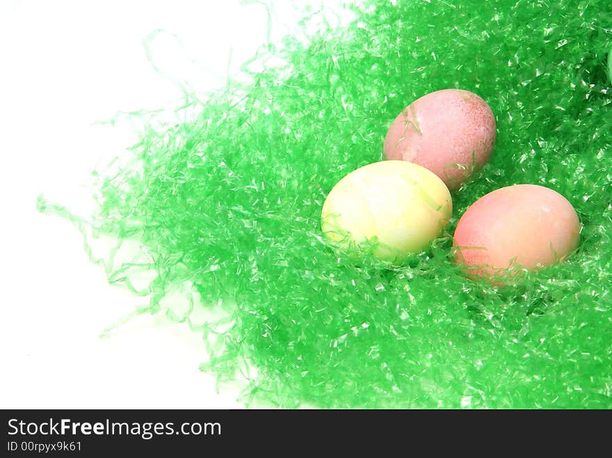 Three pastel colored easter eggs on green easter grass with white copyspace to the side.