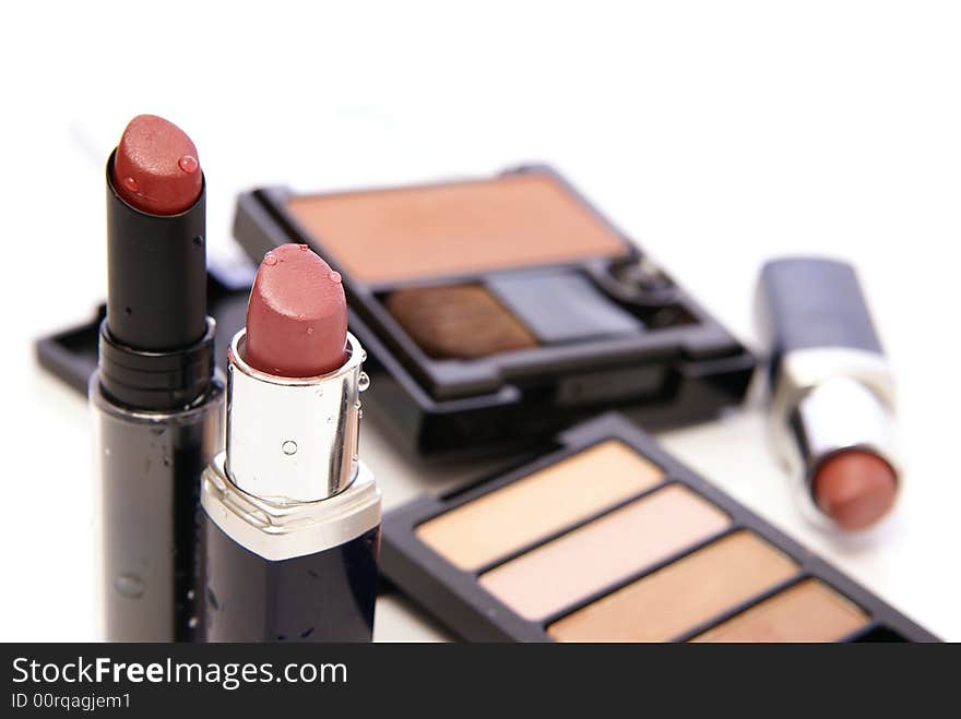 Moist lipsticks in earth tones with related makeup and cosmetics in the background