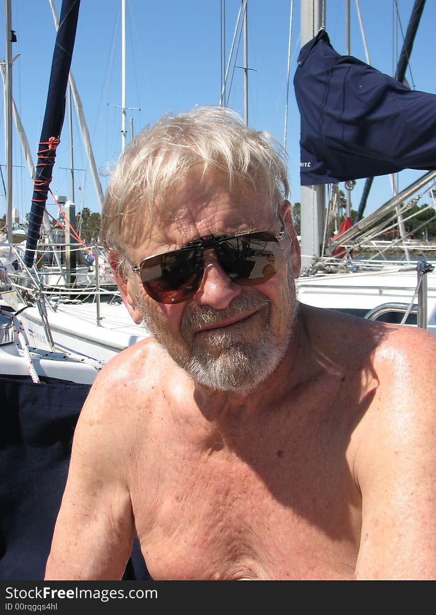 Older confident  seaman captain smiling boat at marina  sunglasses on shirtless in sun. Older confident  seaman captain smiling boat at marina  sunglasses on shirtless in sun