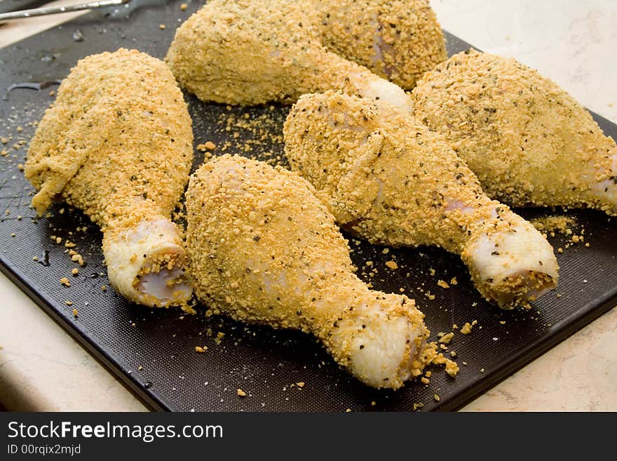 Coated raw chicken drumsticks on desk