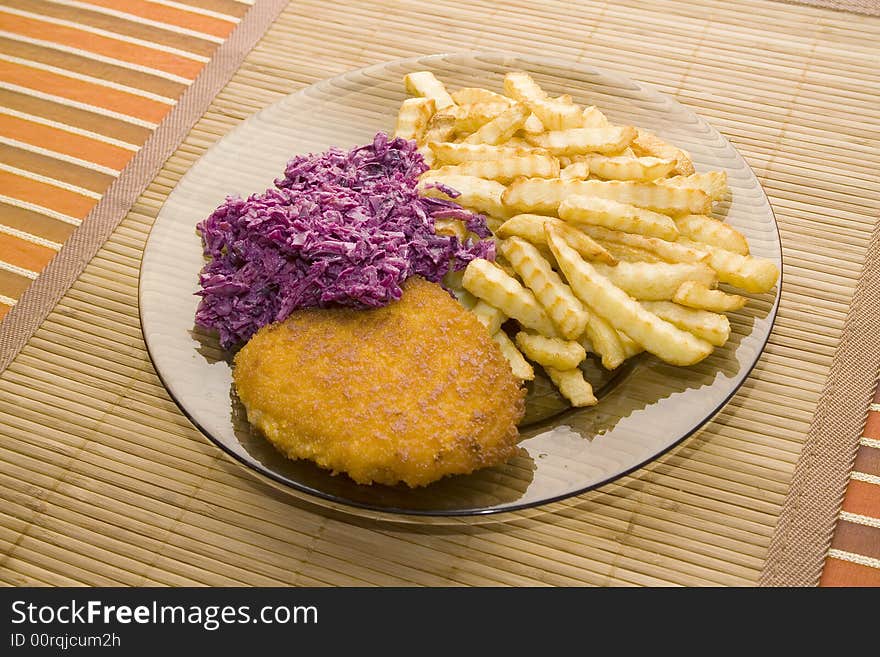 Chicken chop with french fries and salad on the bamboo desk