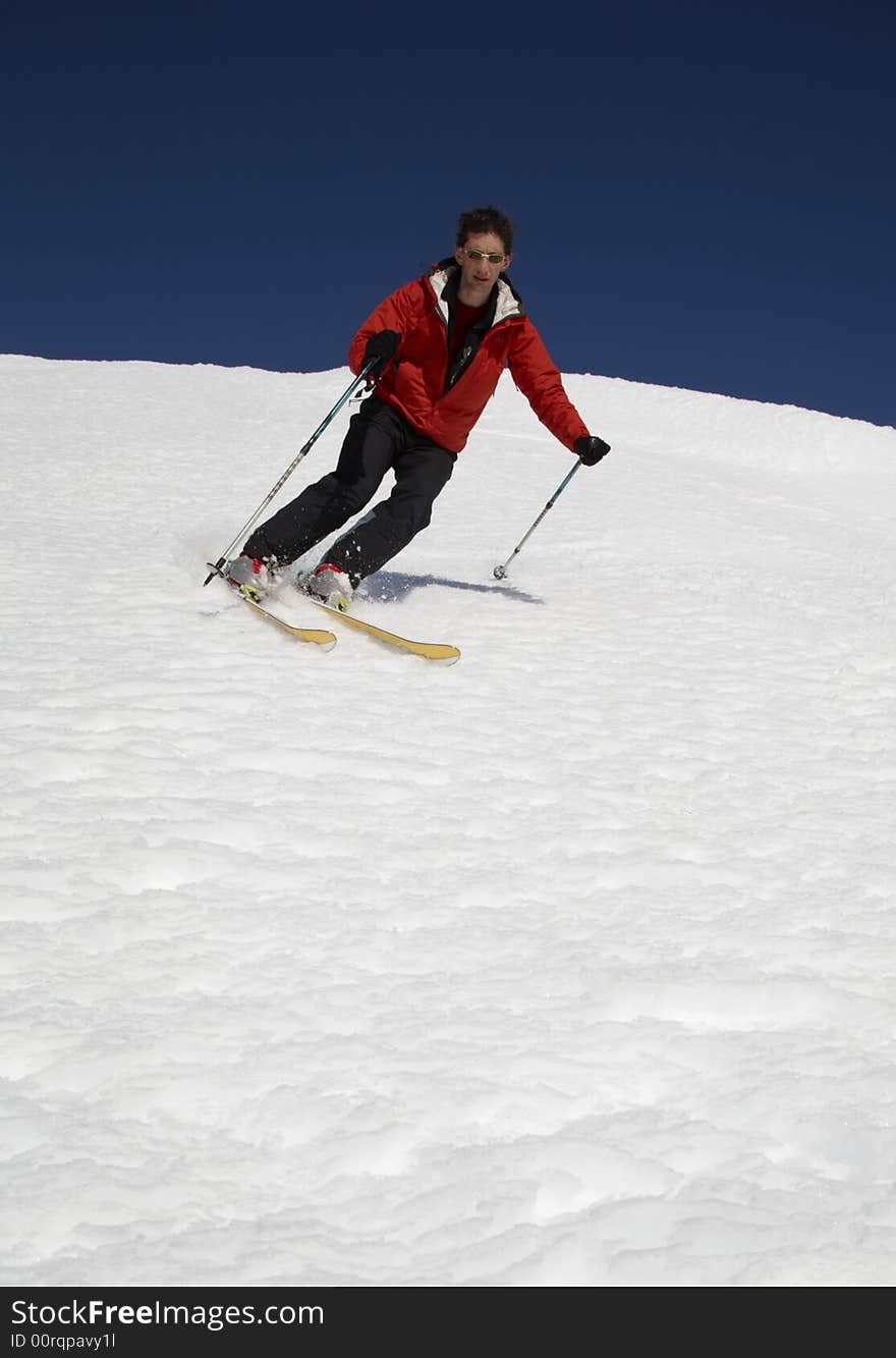 Male skier heading down the slope; blue sky on background; copy-space at the bottom