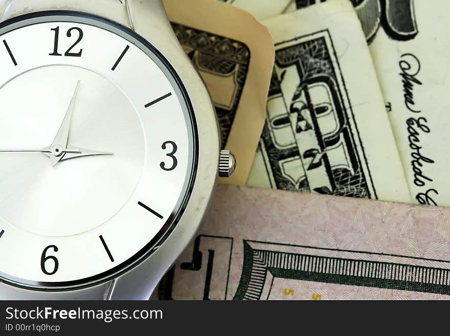 A silver men's wristwatch on American dollar bills. A silver men's wristwatch on American dollar bills